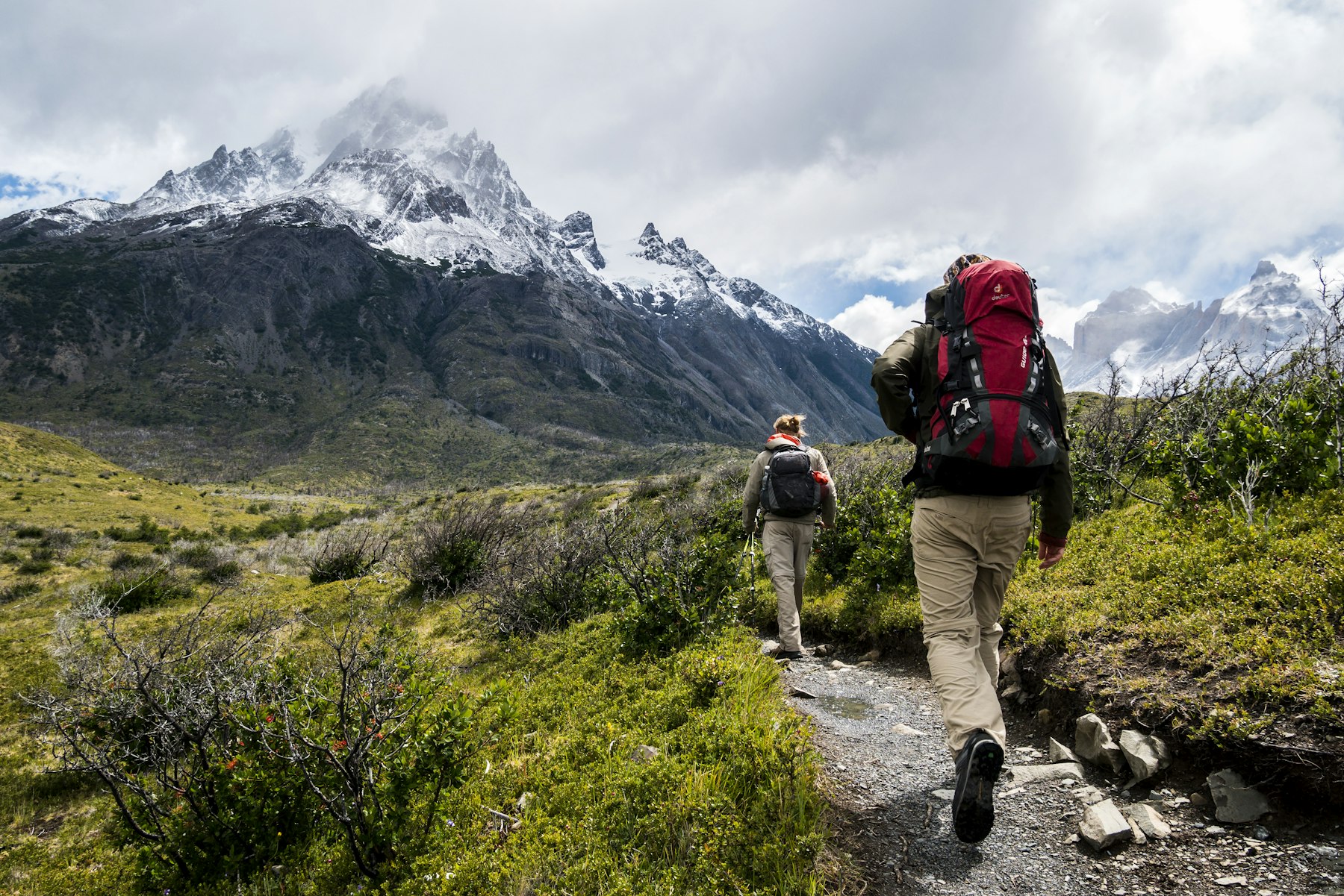 Dua orang hiking bareng ke arah gunung berselimut salju — perjalanan sehat bersama